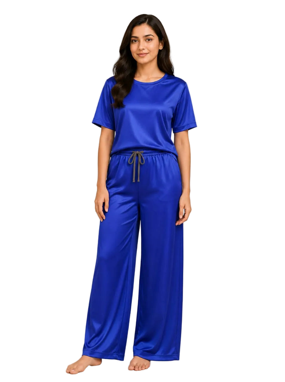 Woman wearing a blue pajama set standing in a room with a plant and framed picture on the wall.